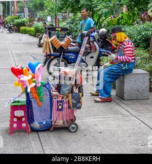 Straßenverkäufer und ein Busker in Clown-Kostüm, der Ballons in Tierformen dreht, die eine Pause machen Jalan Tuanku Abdul Rahman Straße Kuala Lumpur Malaysia Stockfoto