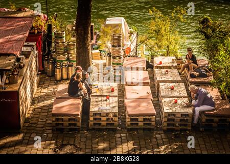 Menschen, die an einer Außenbar in der Herbstsonne am Ufer der seine, Paris, Frankreich trinken Stockfoto