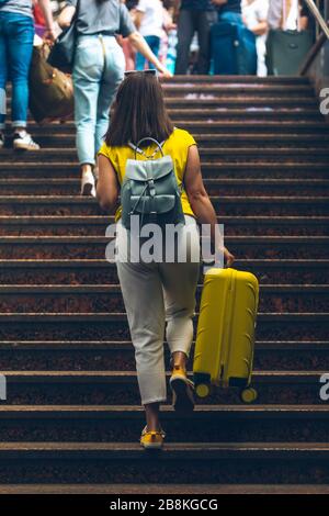 Frau mit gelber Tasche, die am Bahnhof über eine Treppe hinaufgeht Stockfoto