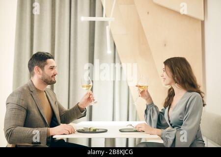 Minimales Seitenansicht Porträt des modernen Paares clinking Champagner Brille bei einem romantischen Aufenthalt im Café, Kopierer Stockfoto