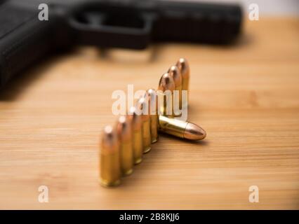 9-mm-Kugeln in einer Reihe mit einer Pistole Stockfoto