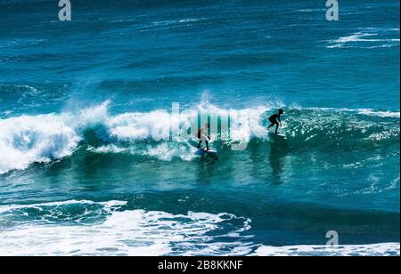 Zwei professionelle Surfer, die in Uluwatu, Indonesien, die großen Wellen schlagen. Stockfoto