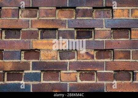 Gebäudewand aus dunklen, gelben bis bräunlichen Klinkersteinen mit verschiedenen Wechselmustern. Die Steine sind in Reihen versetzt, gedreht, eingerückt oder im om Stockfoto