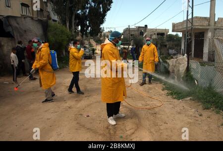 Palästinensische Freiwillige, die Schutzkleidung und Masken tragen, desinfizieren eine Straße als präventive Maßnahme gegen die Verbreitung des neuartigen Coronavirus in Rafah im südlichen Gazastreifen am Sonntag, 22. März 2020. Die Behörden in Gaza bestätigten heute die ersten beiden Fälle von neuartigen Coronavirus, die sie als Palästinenser identifizierte, die nach Pakistan gereist waren und seit ihrer Rückkehr unter Quarantäne gestellt wurden. Die Vereinten Nationen haben gewarnt, dass ein COVID-19-Ausbruch in Gaza katastrophal sein könnte, angesichts der hohen Armutsraten und des schwachen Gesundheitssystems im Küstenstreifen, der seit 2007 unter israelischer Blockade steht. Stockfoto