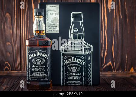 Charkiw, Ukraine, 22. März 2020: Eine volle Flasche amerikanischen Whiskeys Jack Daniel's und eine schwarze Metallbox auf dunklem Holzbohlen im Hintergrund. Starkes Getränk. Il Stockfoto