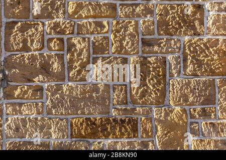 Sandstein-Wand, mit unterschiedlich großen geschärften rustikalen Stein- und weißen Gelenken Stockfoto