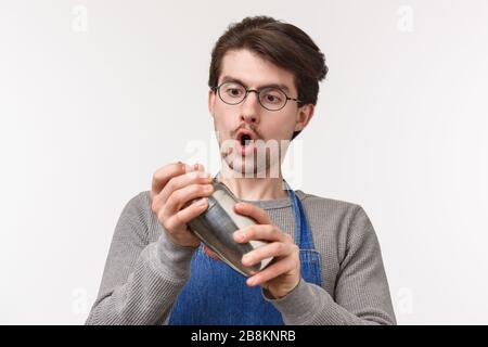 Nahaufnahme des engagierten jungen männlichen Mitarbeiters, Barkeeper macht gerne Getränke, schüttelt Cocktail im Shaker mit Leidenschaft, steht Stockfoto