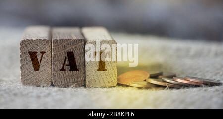 holzblöcke mit Mehrwertsteuer und Geldmünzen. Steuern Gebühren Umsatzsteuer Finanzierung Geschäftskonzept Stockfoto