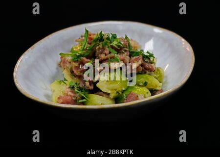 Gekochtes Brüsseler Spross mit Rinderspeck in einer Servierschale mit schwarzem Hintergrund Stockfoto