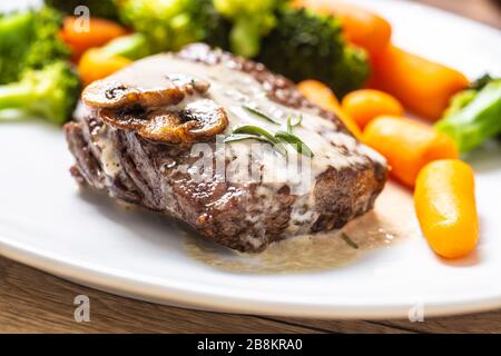 Saftiges Rind Rib Eye Steak mit Pilzsauce und Baby-Gemüse Stockfoto