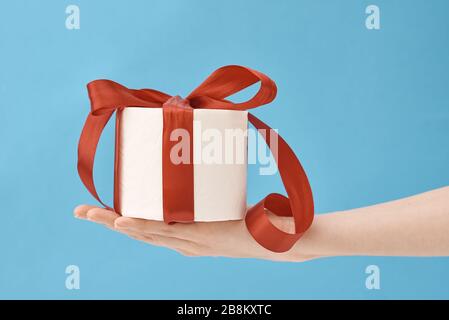 Handgehaltes toilettenpapier in einem festlichen Band als Geschenk auf blauem Hintergrund verpackt Stockfoto