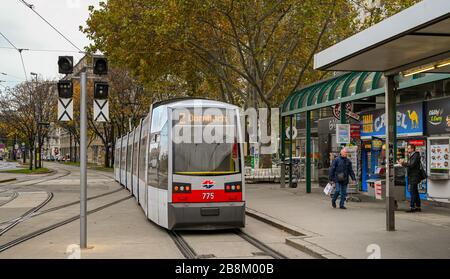 WIEN, ÖSTERREICH - NOVEMBER 2019: Elektrische Straßenbahn nähert sich einer Straßenbahnhaltestelle in der Wiener Innenstadt. Stockfoto