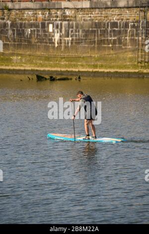 SWANSEA, WALES - JULI 2018: Person, die sich auf einem Paddle-Brett auf dem River Tawe in der Nähe des Yachthafens Swansea aufsteht Stockfoto