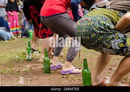 Das Spiel steckt einen Nagel in eine Flasche, die an der Taille befestigt ist Stockfoto