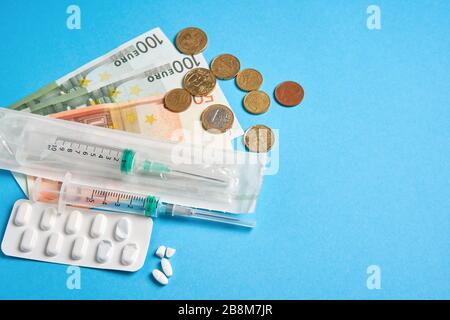Pillen leere Blister für Medikamente individuelle Spritze und Geld liegen auf einem blauen Hintergrund Teures Krankenversicherungskonzept für Medikamente. Teure Behandlung Stockfoto