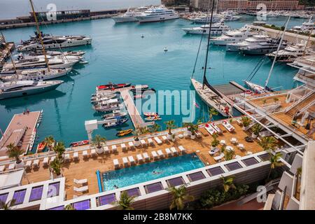 Monaco - 16. April 2018: Monaco Yacht Club - YCM, Terrasse mit Deckcheairs und Schwimmbad und Hafen, Blick von oben Stockfoto