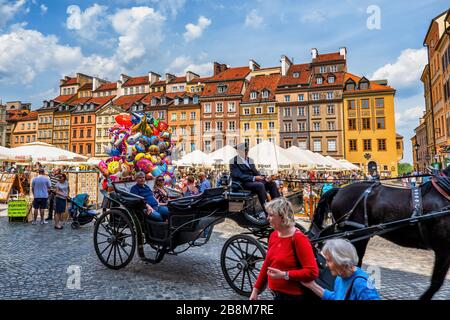 Warschau, Polen - 25. Mai 2019: Menschen auf dem belebten Altstädtischen Marktplatz in der Hauptstadt, Pferdekutsche, Ballons und historische Häuser Stockfoto