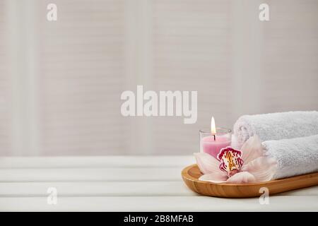Spa-Zusammensetzung mit aromatischen Kerzen, Orchideenblume und Handtuch auf weißem Holztisch. Beauty-Spa-Behandlung. Kopierer Stockfoto