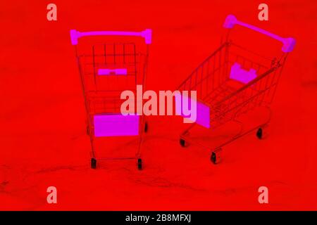 Einkaufswagen aus Edelstahl. Metall-Supermarkt-Einkaufswagen. Zwei leere Einkaufswagen auf rotem Grund. Shopping-Konzept. Stockfoto