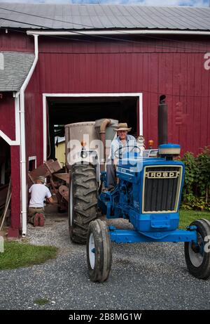 Amerikanischer Bauer auf blauem Traktor, Red Barn Stockfoto