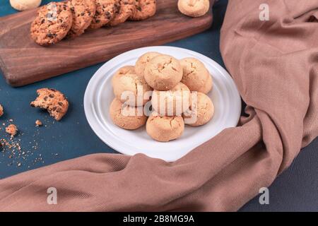 Butterkekse in weißer Platte und Haferflocken auf blauem Tisch Stockfoto