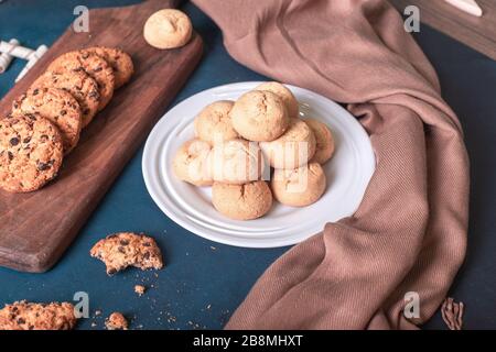 Butterkekse in weißer Platte und Haferflocken auf blauem Tisch. Draufsicht Stockfoto