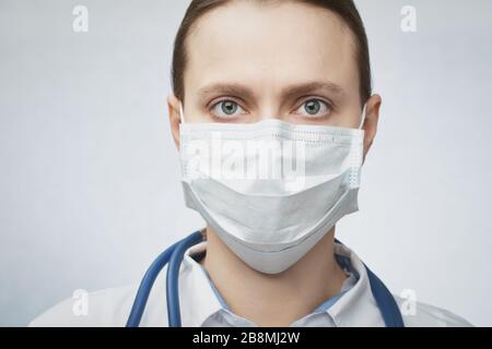 Nahaufnahme des selbstbewussten jungen Arztes, der eine schützende Operationsmaske trägt Stockfoto