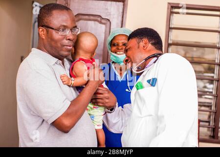 Ein junger Mann fängt sein Baby während des Arztes untersucht es im Krankenhaus. Stockfoto