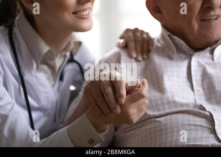 Nahaufnahme, zugeschnittene Bildschwester, die die Hand des alten Mannpatienten hält Stockfoto