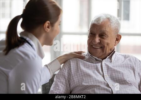 Pflegende Altenpflegerin im weißen Mantel sorgt für älteren Mann Stockfoto