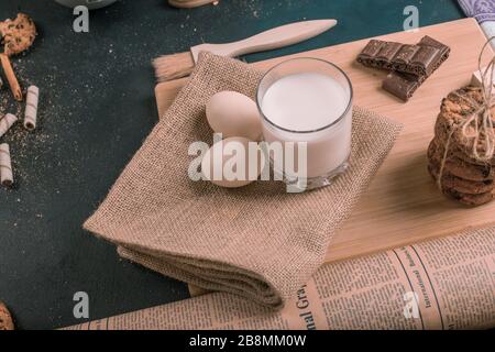 Haferflocken mit Schokoladenchips, Eiern und einem Glas Milch auf einem Holzbrett Stockfoto