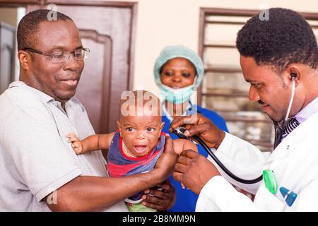 Ein junger Mann fängt sein Baby während des Arztes untersucht es im Krankenhaus. Stockfoto