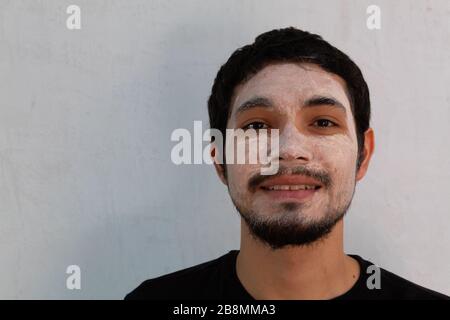 Porträt eines jungen hispanischen Mannes mit Bart, der eine Hydriermaske auf weißem Hintergrund trägt Stockfoto