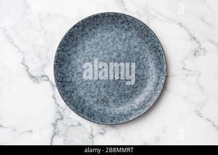 Blaue Platte auf weißem Marmorhintergrund. Leere Platte mit Kopierbereich für Text oder Design. Modernes, modernes Küchenkonzept Stockfoto
