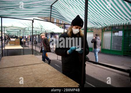 Hackney und Kovid 19. Broadway-Markt. Markthändler trägt Gesichtsmaske neben leerem Stall. Stockfoto