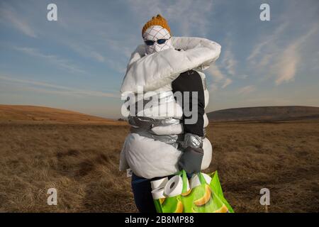 Perthshire Hills, Großbritannien. März 2020. Bild: Konzeptbild einer Person, die sich in der Mitte des Nirgendwo selbst isolieren wird und den begehrtesten Gegenstand in der Welt des toilettenpapiers trägt, während sie in hausgemachte persönliche Schutzausrüstung eingewickelt ist. Kredit: Colin Fisher/Alamy Live News Stockfoto