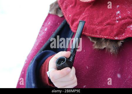 Der Mann in der mittelalterlichen Kleidung hält eine Pfeife in der Hand. Stockfoto