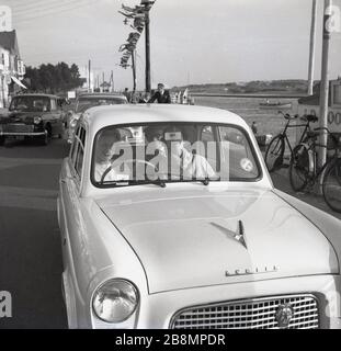 1950er Jahre, historisch, ein Tag aus... drei Damen sitzen in einem beliebten Auto der Ära, einem zweitürigen Ford Anglia 100E, am Fluss Frome, in der Nähe von Sodbury, England, Großbritannien. Stockfoto