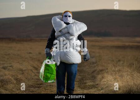 Perthshire Hills, Großbritannien. März 2020. Bild: Konzeptbild einer Person, die sich in der Mitte des Nirgendwo selbst isolieren wird und den begehrtesten Gegenstand in der Welt des toilettenpapiers trägt, während sie in hausgemachte persönliche Schutzausrüstung eingewickelt ist. Kredit: Colin Fisher/Alamy Live News Stockfoto