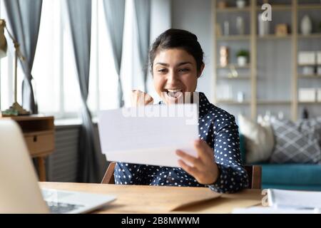 Aufgeregtes indisches Mädchen, das gute Nachrichten in einem Brief liest Stockfoto