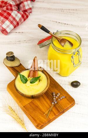 Ghee oder geklärte Butter im Mixbecher. Gesunde Ernährung und Verwendung von frisch zubereiteten Produkten aus biologischem Anbau. Gesunde Zutat zum Kochen organischer Speisen. Löffel mit Ghee aber Stockfoto