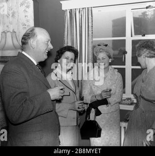 1962, historische, gut gekleidete, reife Menschen, die sich auf einer Jubiläumsfeier in einem Haus in England, Großbritannien, erfreuen. Stockfoto