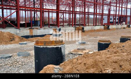 Baustelle eines Lagerhauses. Betonbrunnen für Wasserversorgung und Kanalisation. Stockfoto