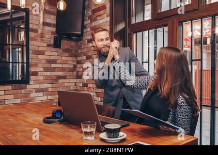 Fröhliche kaukasische Kollegen, die fünf hohe Personen geben und Erfolg feiern, gute Nachrichten online in einem Laptop oder Teamwork lesen. Motivierte Kollegen teilen Stockfoto