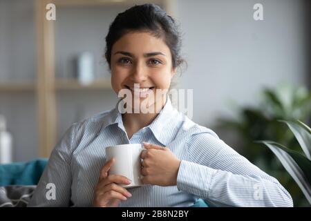 Kopfschuss Porträt lächelnde indische Frau mit weißem Becher Stockfoto