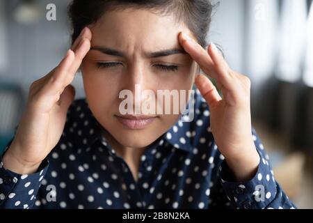 Erschöpftes indisches Mädchen, das Stirn berührt und Kopfschmerzen hat, schließen Stockfoto