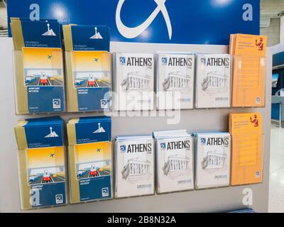 Athen, Griechenland - Februar 11 2020: Internationaler Flughafen Athen Eleftherios Venizelos. Ein Stand mit Papierkarten von Athen und Flughafen, Führer Stockfoto