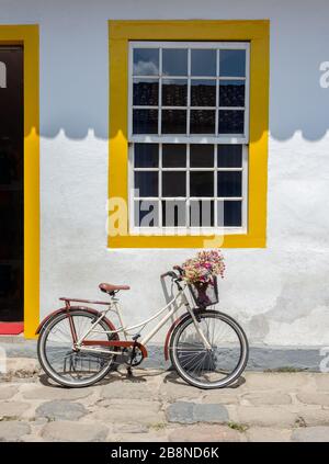 Ein Fahrrad, das vor einem farbenfrohen Haus in der historischen Stadt Paraty in Brasilien geparkt wurde. Das erhaltene koloniale Zentrum der Stadt wurde in die UNESCO aufgenommen Stockfoto