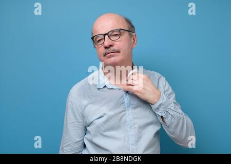 Müder älterer Mann in Brille, der sich vergackelt, Schweiß aus dem Hals schwitzt Stockfoto