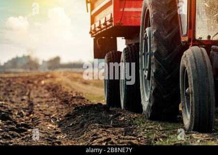 Alten roten landwirtschaftlichen Traktor mit Anhänger auf Schmutz Landstraße im Frühjahr am Nachmittag Stockfoto